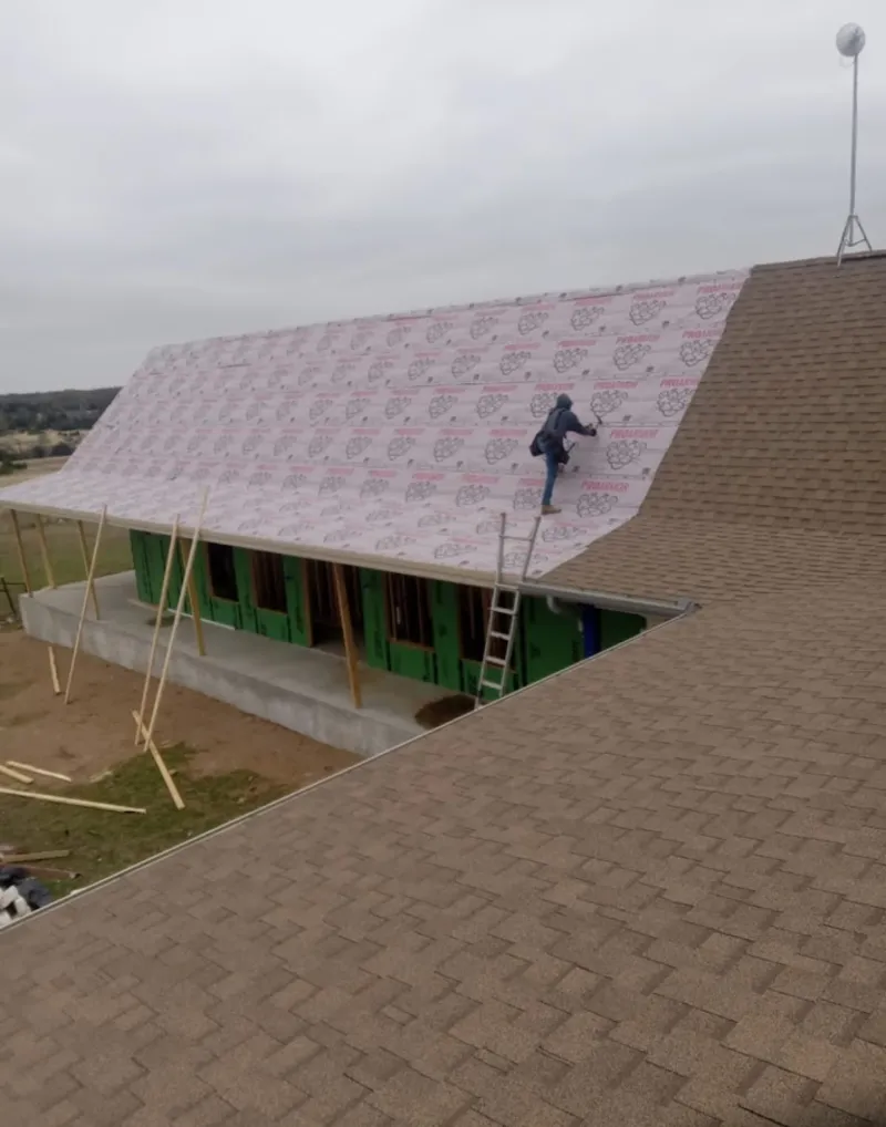 Worker preparing underlayment for a metal roof installation in Brownville